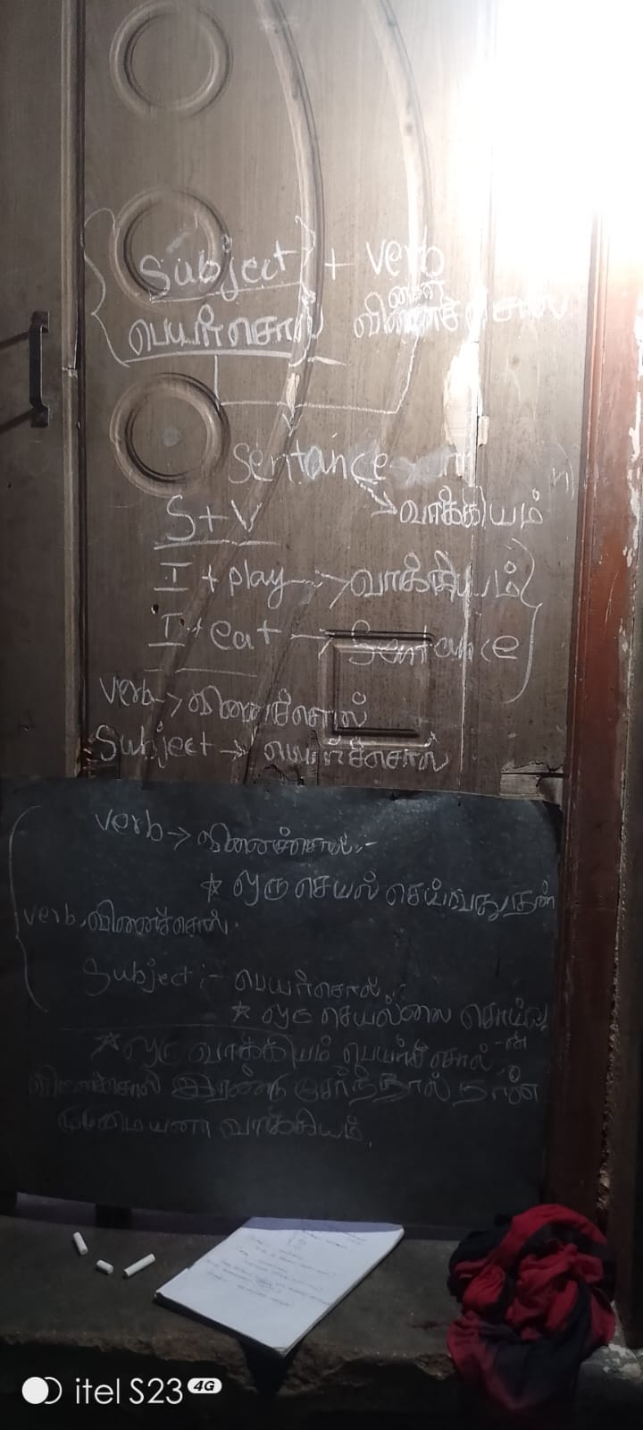 Lessons in English grammar and Tamil chalked onto a wooden door, used as a blackboard before the donation